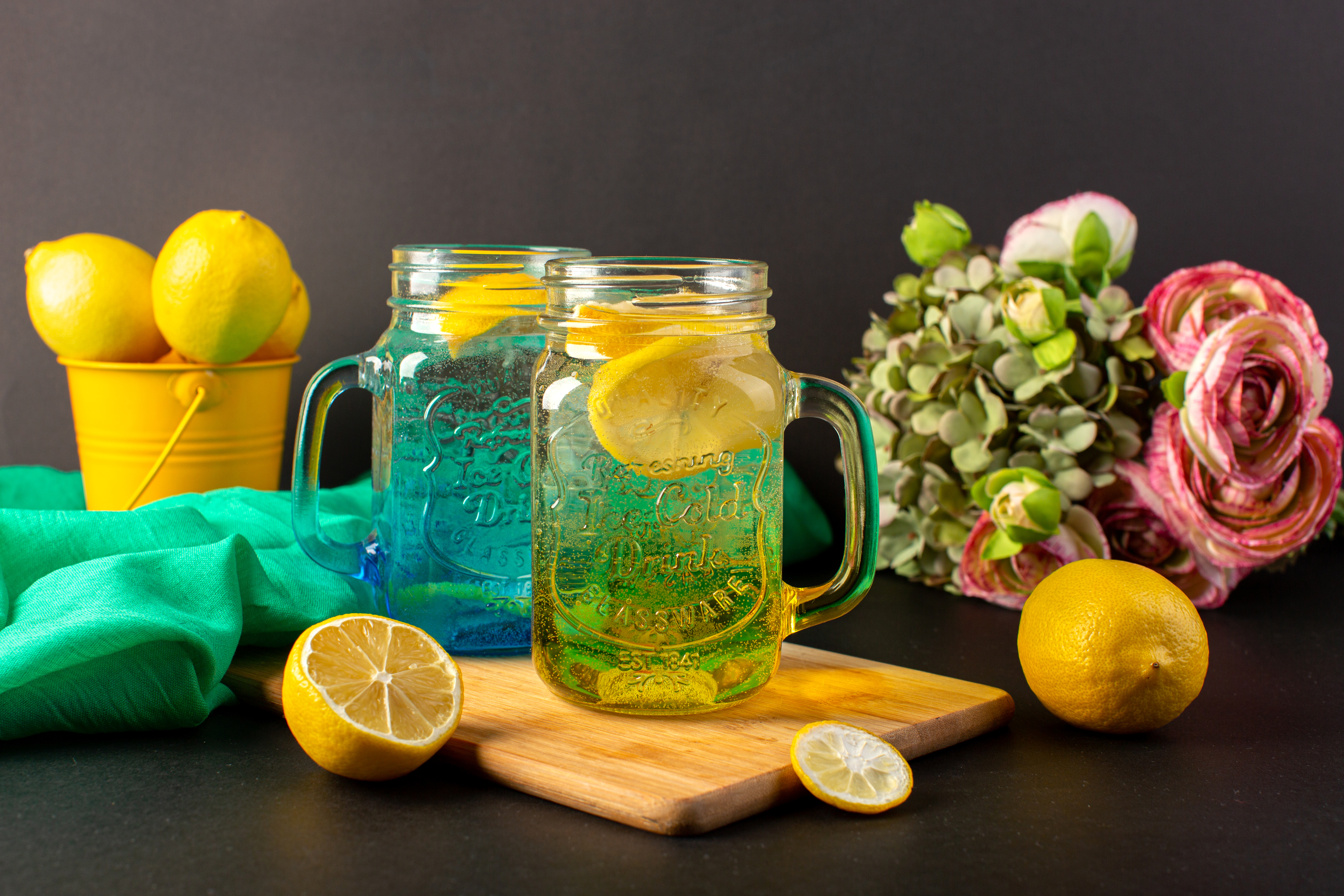front-view-lemon-cocktail-fresh-cool-drink-inside-glass-cups-sliced-whole-lemons-along-with-flowers-dark-background-cocktail-drink-fruit