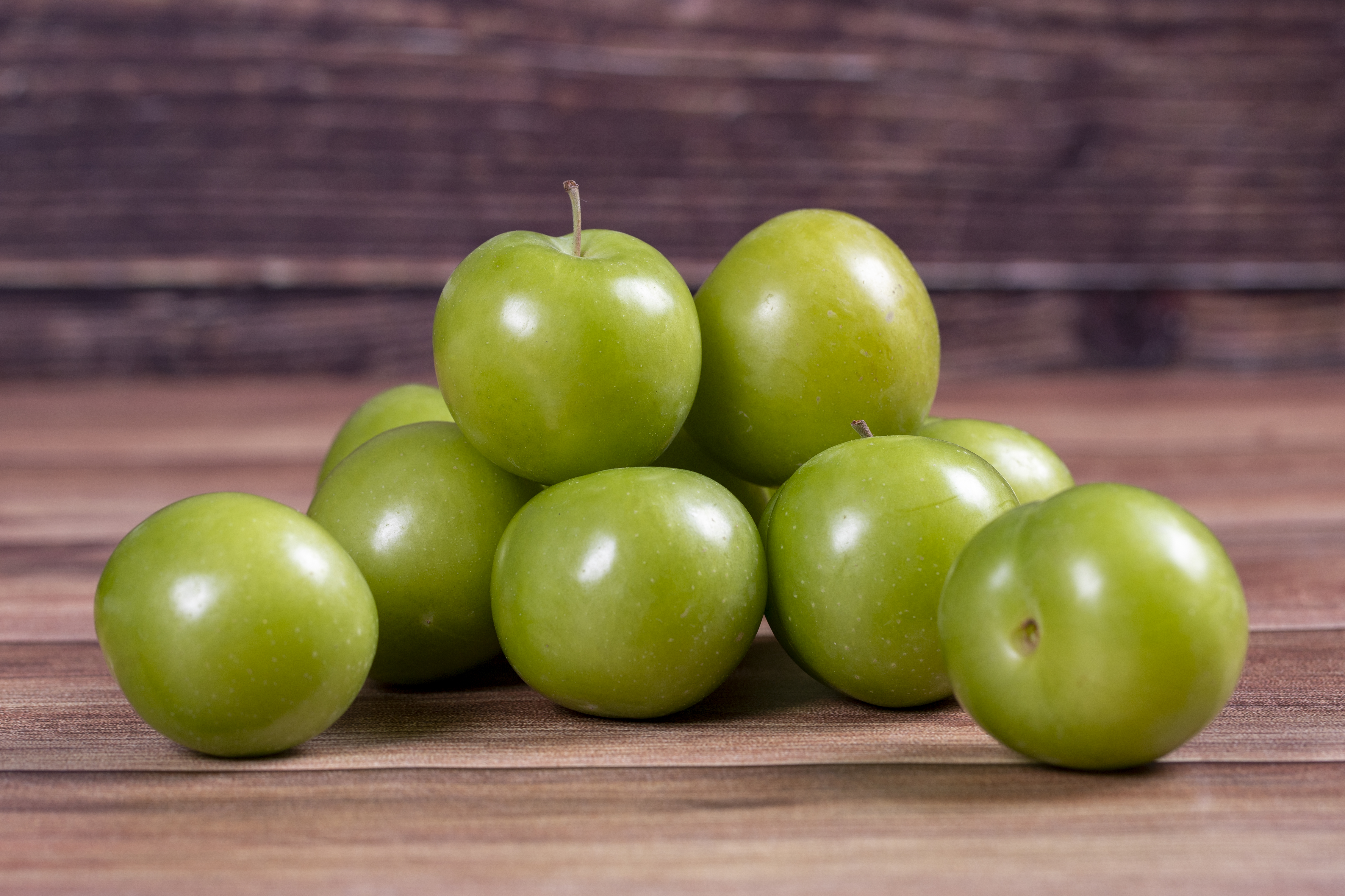green-plum-wood-background-pile-green-plums-close-up