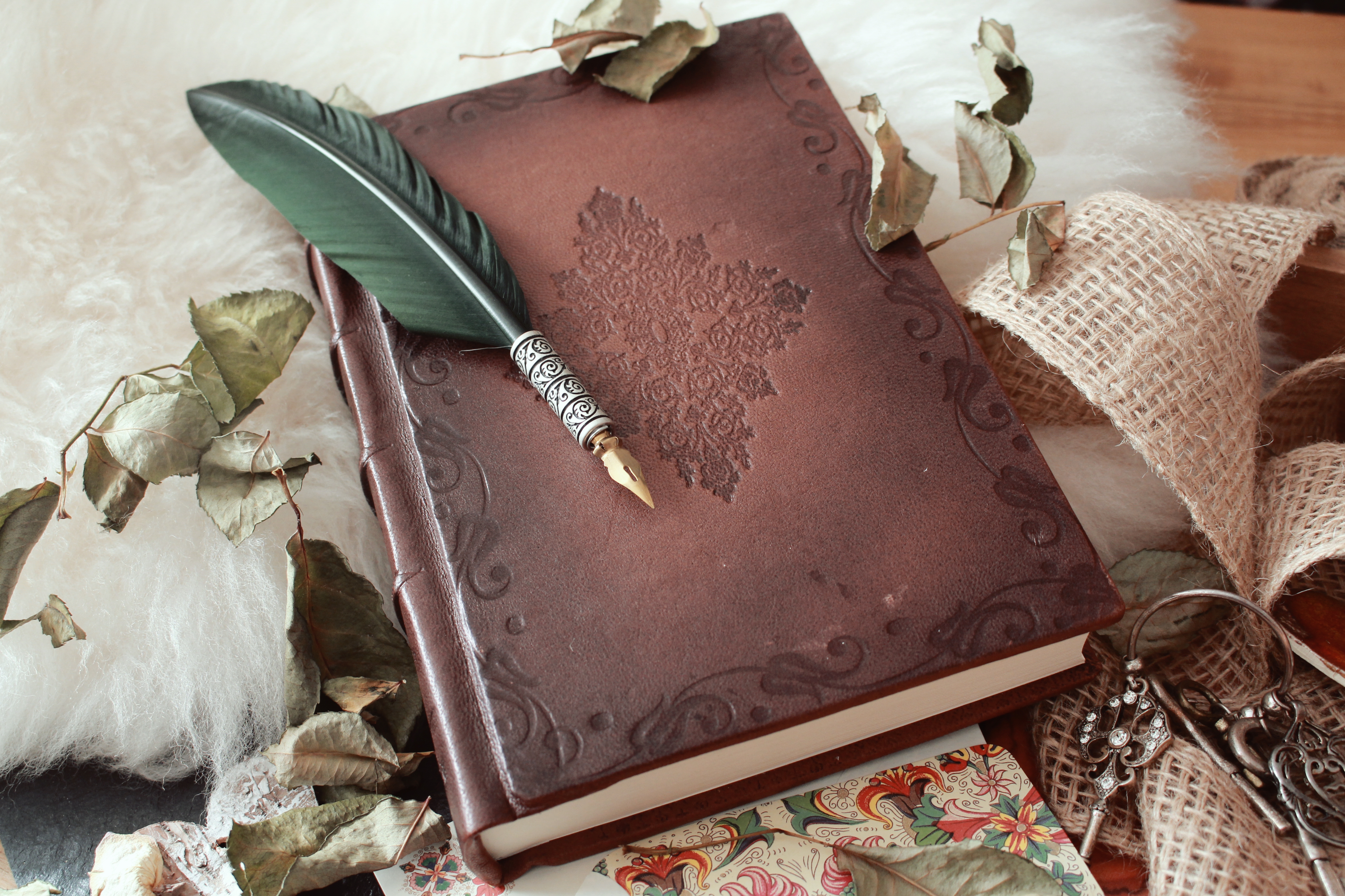 high-angle-shot-quill-pen-old-book-covered-with-dried-flower-petals