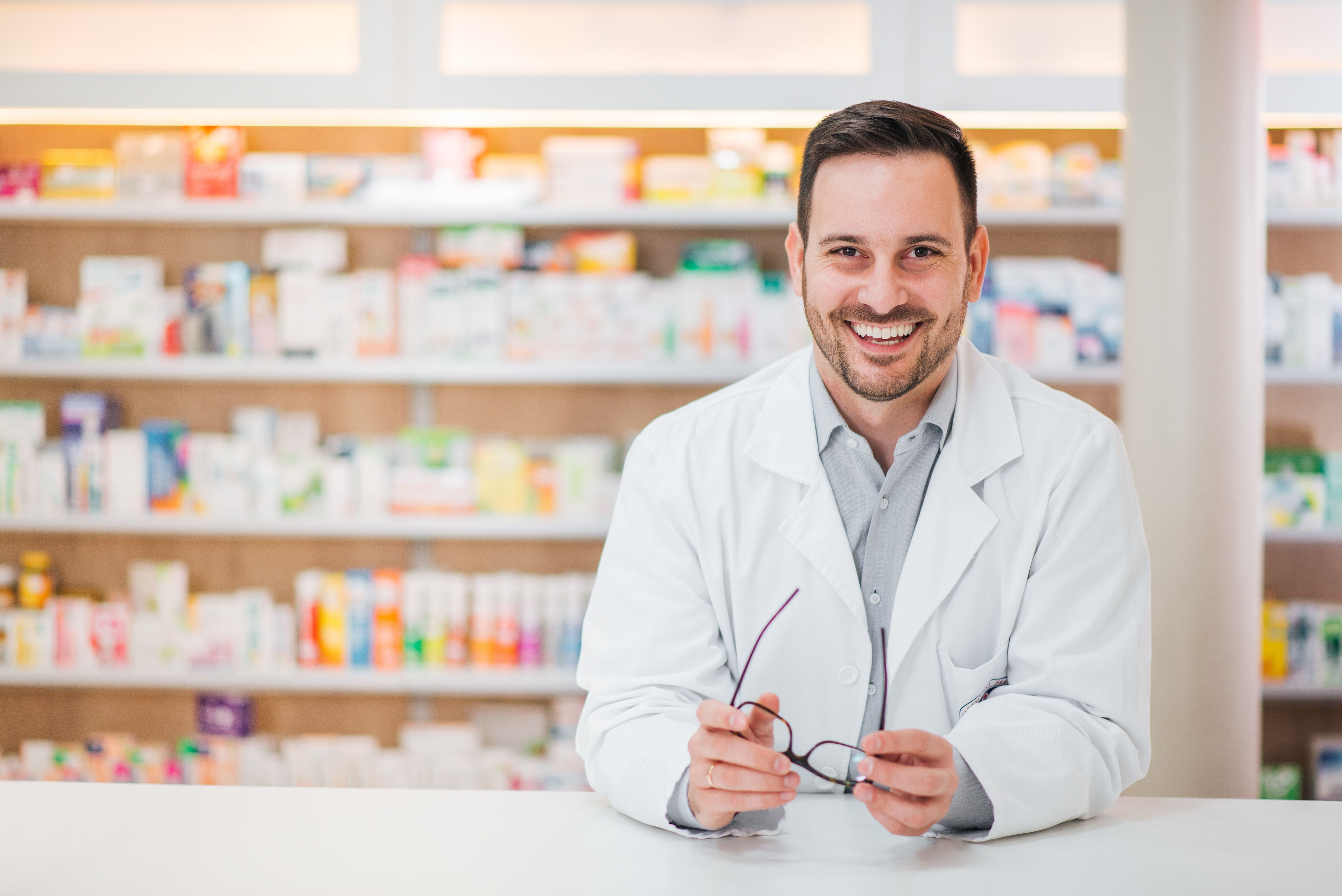 portrait-cheerful-handsome-pharmacist-leaning-counter-drugstore