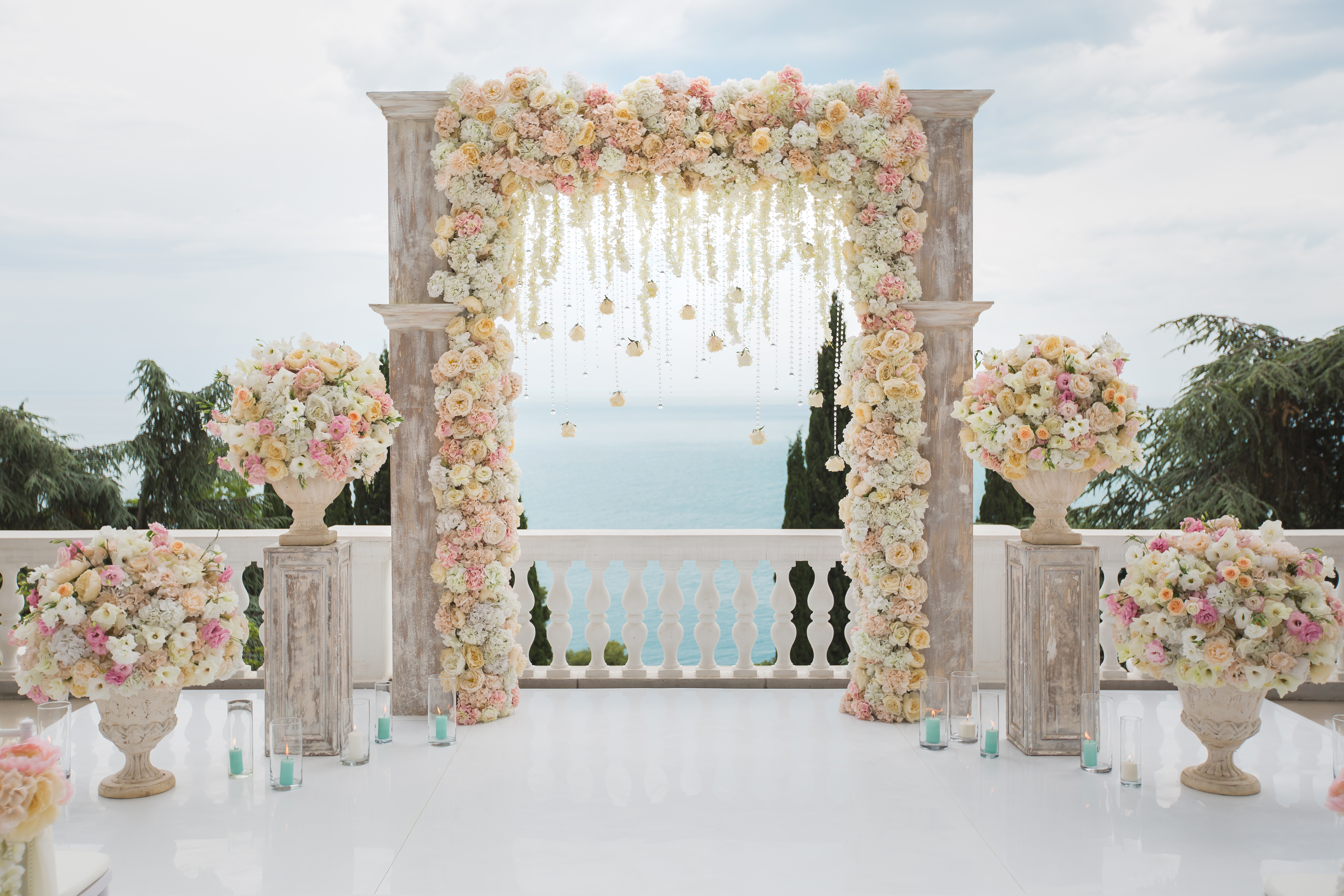 elegant-wedding-arch-with-fresh-flowers-vases-ocean-blue-sky