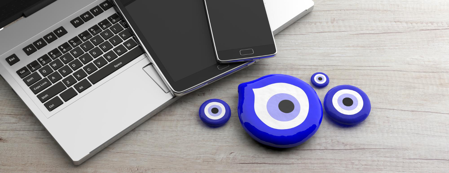 evil-eye-amulet-miscellaneous-sizes-protection-with-laptop-smartphone-wooden-office-background-3d-illustration