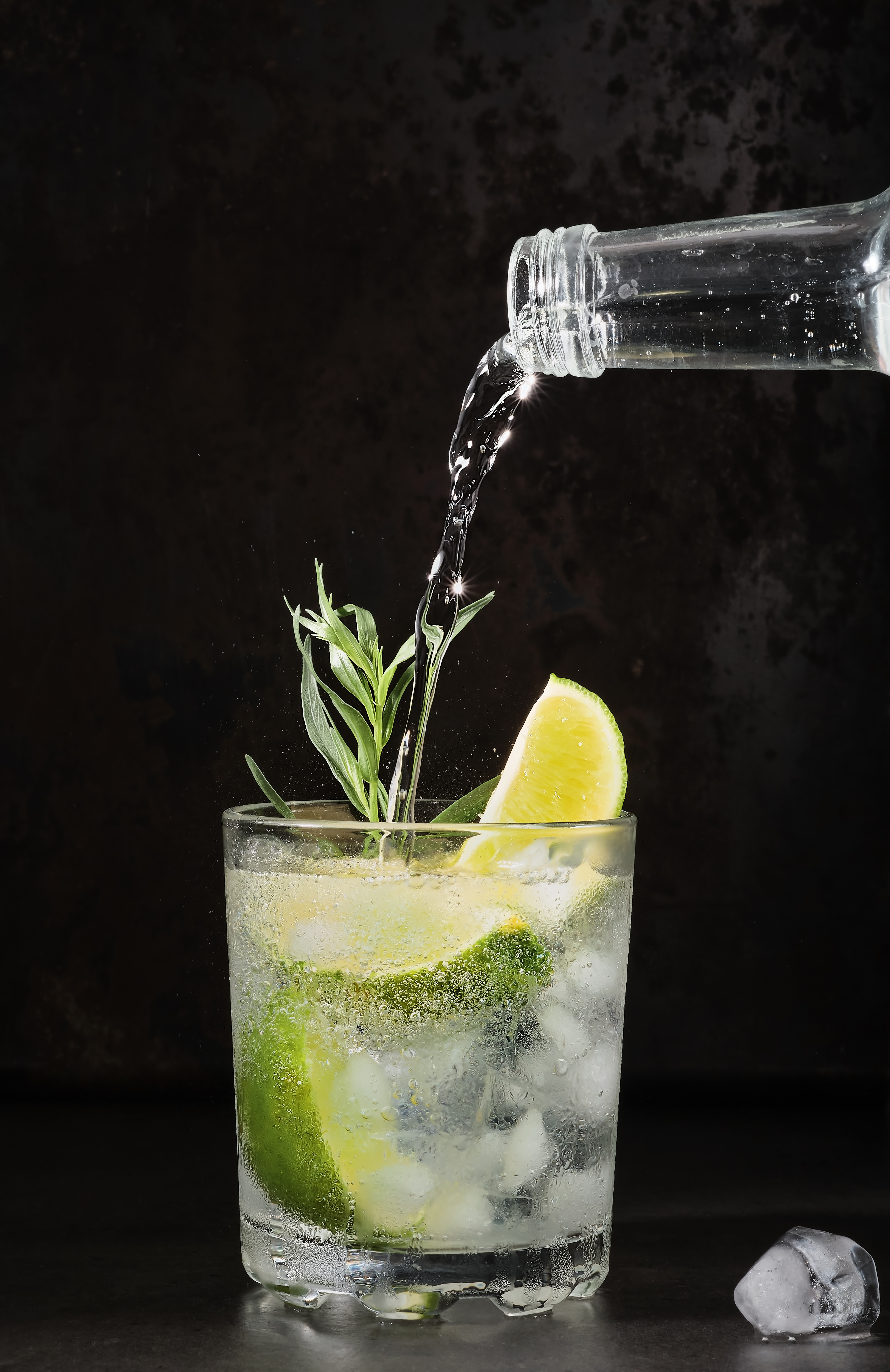 glass-lime-lemonade-dark-table-summer-drinks-pure-mineral-water-is-poured-into-glass-vertical-frame-selective-focus-homemade-drink-with-lime-tarragon-ice-cubes-cold-fresh-drinks-idea