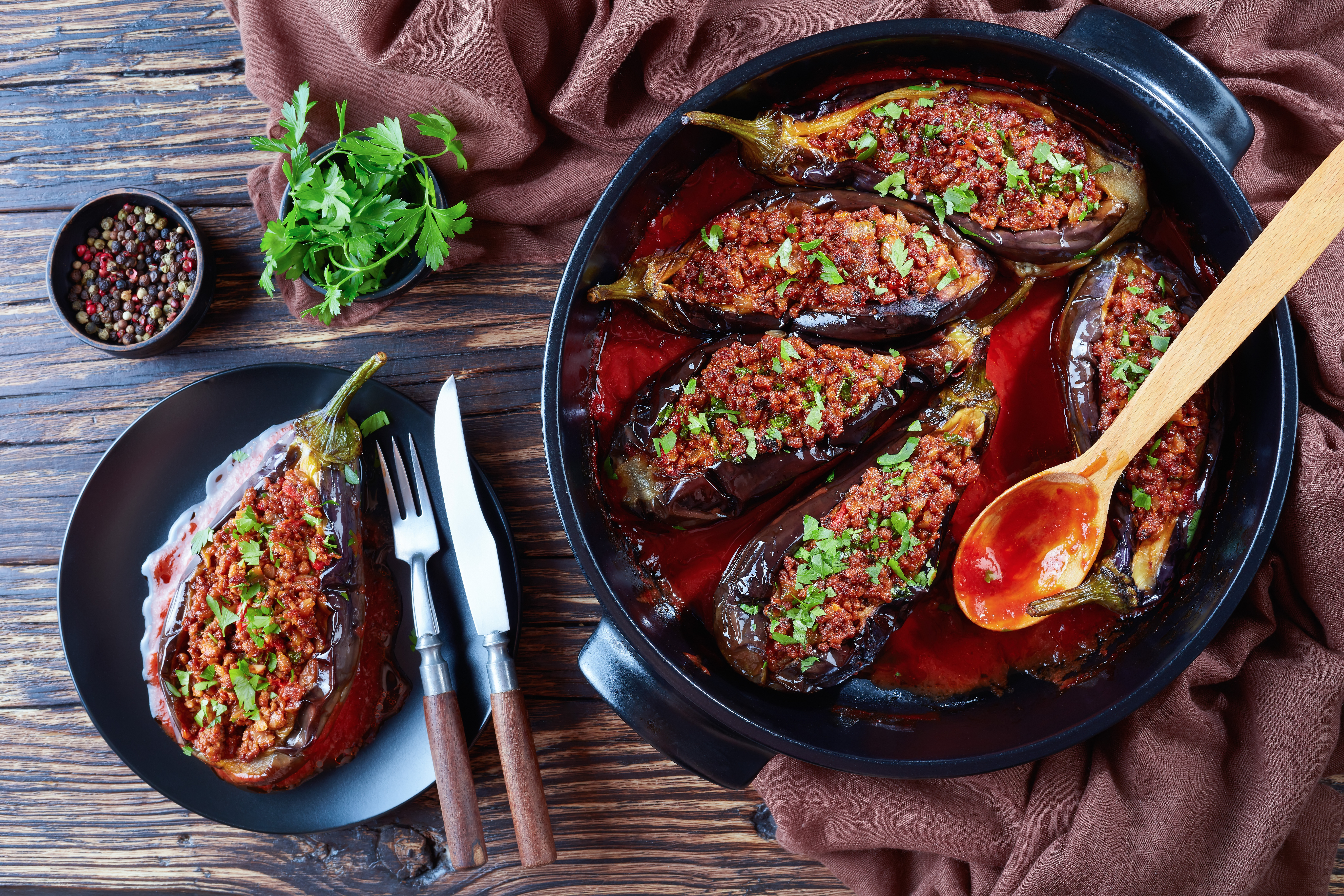 karniyarik-stuffed-eggplants-aubergines-with-ground-beef-vegetables-baked-with-tomato-sauce-served-plate-with-fork-knife-turkish-cuisine-horizontal-view-from-close-up-flatlay
