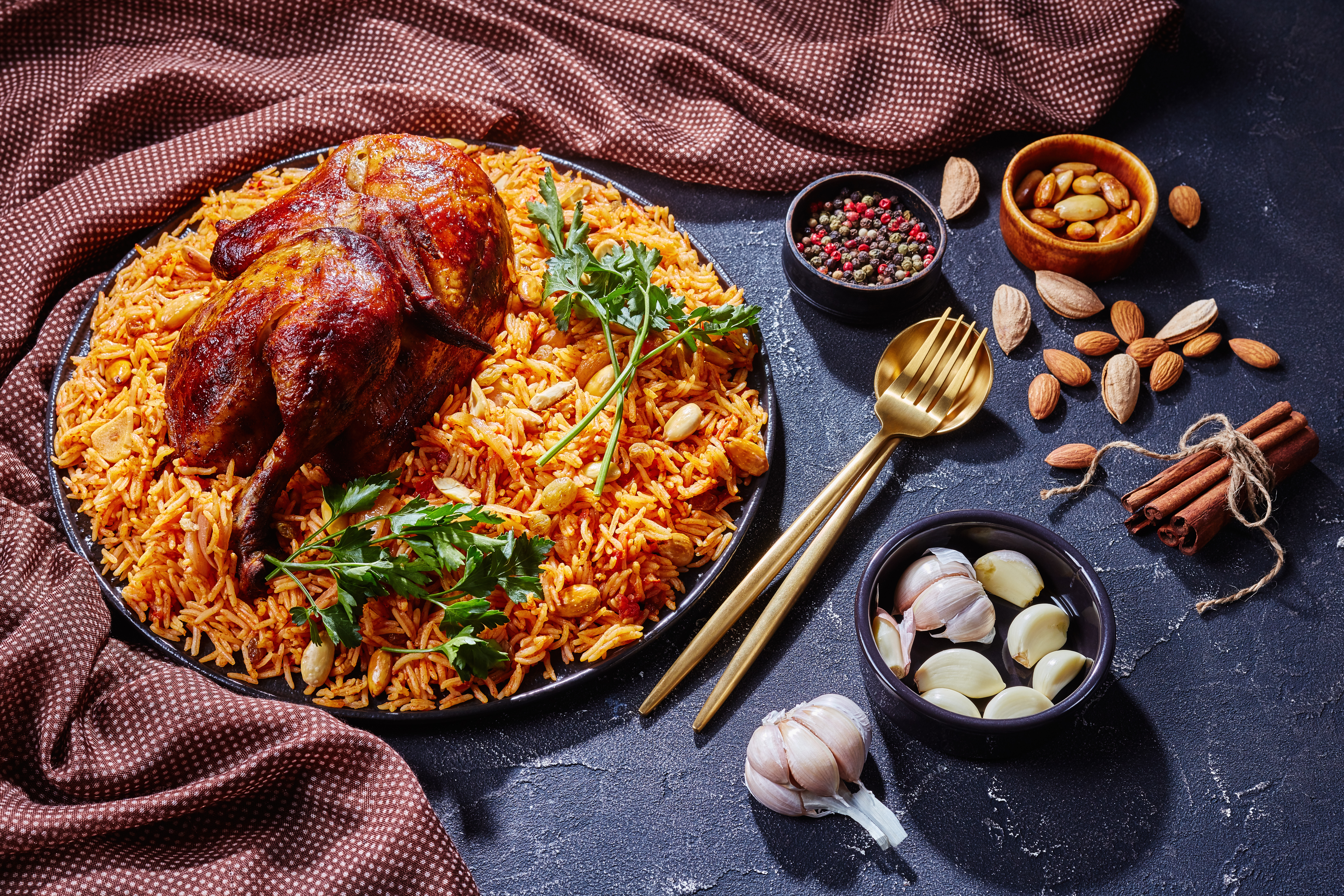saudi-arabian-kabsa-spiced-chicken-quarter-rice-roasted-almonds-raisins-garlic-black-plate
